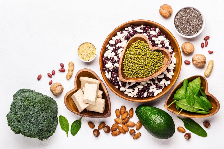 Assortment of high fiber foods including berries, whole grains, beans, and vegetables displayed on a wooden table for digestive health